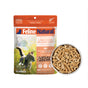 A pack of Feline Natural Grain-Free, Freeze-Dried Cat Food sits next to a bowl of light brown pellets. The package shows a cat outdoors and promotes natural ingredients.