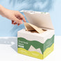 A hand pulls a facial towel from a white and green Fomin Clean Facial Towels Bamboo box, which highlights benefits for sensitive skin like natural antimicrobial properties and acne reduction. Light blue background.