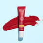 A red tube of FRÉ Skincare PLUMP ME Peptide Lip Tint Mineral SPF 30 sits atop a swipe of red lip tint on a light blue background.