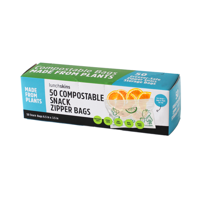 The green and blue Lunchskins box, featuring a sandwich, lemon slices, and a cucumber, contains 50 Ziptop Compostable Snack Bags made from plant-based materials. These bags are leak-resistant for eco-friendly disposal.