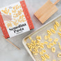 The FarmSteady Semolina Pasta Making Kit, accompanied by a wooden cavatelli board for shaping authentic Italian pasta, and fresh pasta shapes resting on a parchment-lined baking sheet are displayed on a light surface.