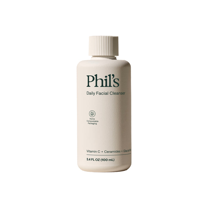 A beige bottle of Phil's Daily Facial Cleanser with a ribbed cap. The minimalist label spotlights its antioxidant formula with Vitamin C, Ceramides, Glacier ingredients, in a 3.4 fl oz (100 mL) compostable package.