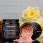 Two jars of Chagrin Valley Soap & Salve Rose & Hibiscus Clay Face Mask are displayed—one upright, one spilling pink powder. French Pink Kaolin Clay, organic hibiscus, and yellow roses brighten the background.