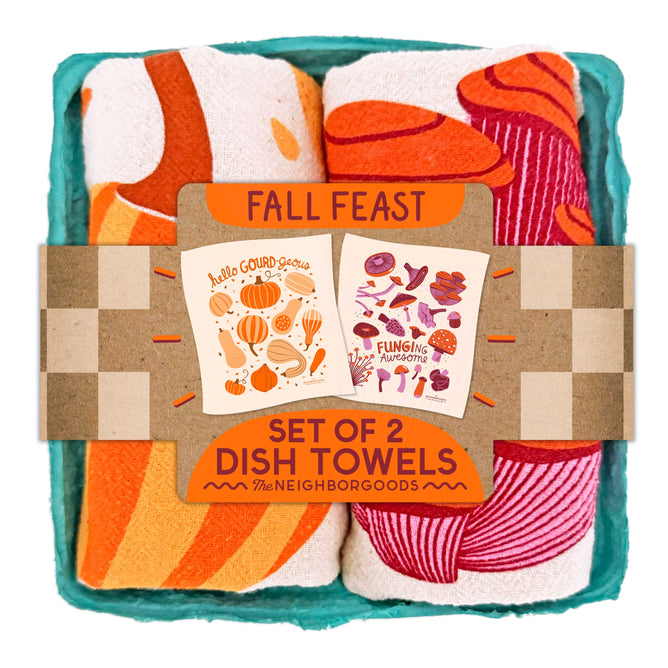 Two cotton dish towels—one with orange gourds, one with mushrooms—come rolled in a teal box labeled “Dish Towel Set of 2 - Fall Feast” by The Neighborgoods. Colorful, gift-ready kitchen towels for any occasion!.