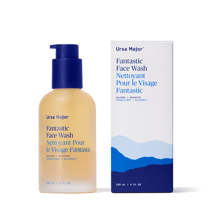 A bottle of Ursa Major Fantastic Face Wash with a blue pump stands beside its matching box, both labeled in English and French. The daily cleanser is naturally nourishing, and the box has blue mountain graphics at the base.