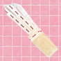 The Floofah 2-in-1 Exfoliating Back Scrubber, a biodegradable loofah sponge featuring two white fabric handles with red text, rests on a pink tiled surface.