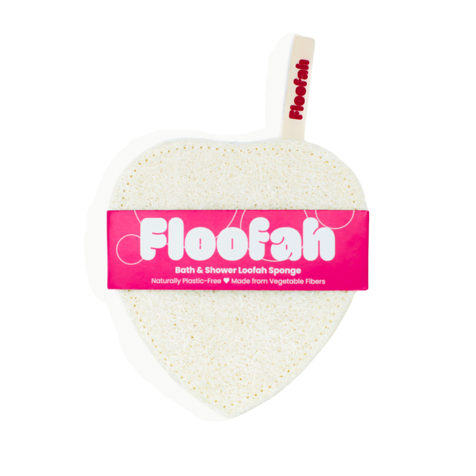 A heart-shaped, white Exfoliating Shower Loofah by Floofah features a pink label and a small tag. Its packaging highlights that it is made from vegetable fibers and plastic-free, providing a sustainable, plant-based option for cleansing.