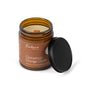 A brown glass jar candle labeled Cinnamon Orange Clove, with a black lid beside it, is made by Fontana Candle Co.; this natural scented candle features a wooden wick and is crafted from beeswax and coconut oil.