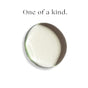 A circular dollop of white cream with a translucent edge rests on a white background. Above it, black text reads: Foria Intimacy Awaken Arousal Oil with Organic Botanicals.