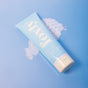 A light blue tube of Foxly Body Lotion rests on a blue surface with a swirl of white lotion beside it. Infused with nourishing oils and midnight vanilla scent, this 230 mL tube provides superior skin hydration.