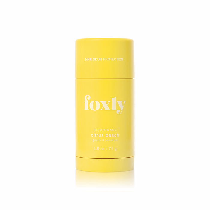 A bright yellow Foxly Deodorant stick, labeled "Citrus Beach" and "Gentle & Sensitive" with “24-hour odor protection” near the top, stands upright against a white background.