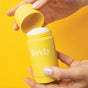 Someone opens a yellow Foxly Deodorant against a matching yellow background. This aluminum-free deodorant offers 24-hour odor protection.