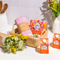 A woven basket with a pink towel and Grove Co. laundry detergent sheets sits nearby the Grove Co. Dish Soap Set - Summer Collection, flowers, kitchen utensils, and hand soap, all arranged against a tiled wall.