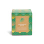 A green box with a gold and teal art deco pattern houses the Grove Co. Soy Wax Blend Candle - Winter Collection, labeled “enchanted forest” with notes of balsam, sweet juniper, crisp cedar, oak moss, and twinkle lights.