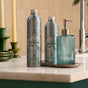 Two bottles of Grove Co. Hand Soap Refill - Winter Collection sit beside a ribbed blue dispenser on a marble countertop, with green candles and winter collection decor in the background.