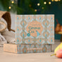 A box of Grove Co. Laundry Detergent Sheets - Winter Collection sits on a table, its brown packaging with teal and gold designs featuring pears and geometric patterns, emphasizing bio-based ingredients.