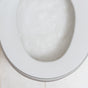 Close-up of a toilet bowl with white, bubbly water inside—thanks to Grove Co. Toilet Bowl Cleaner Pods that fight hard water stains—seen from above against a tiled floor background.
