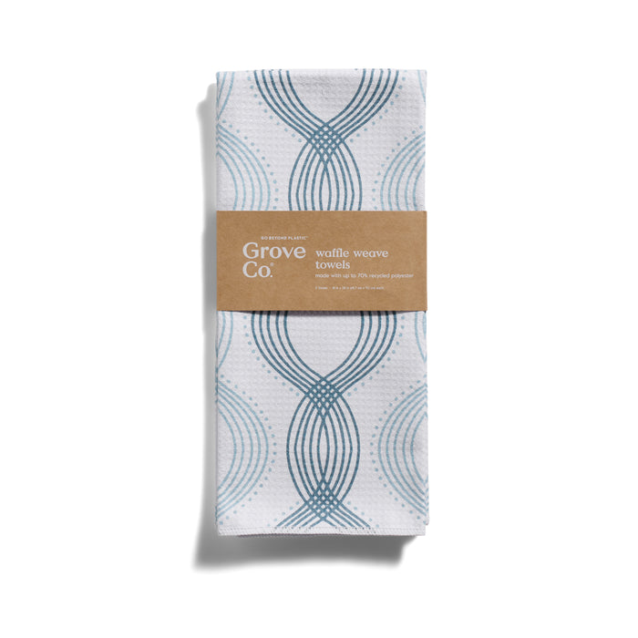A folded Grove Co. Waffle Weave Towel from the Winter Collection, featuring blue circles and waves on white, with a brown paper label around the center.