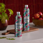 Two Grove Co. Dish Soap Refill - Fall Collection bottles with floral designs sit on a white countertop with red apples and green leaves, evoking fall scents. The aluminum bottles are recyclable.