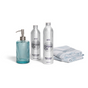 The Grove Co. Hygge Home Set - Winter Collection features a blue glass soap dispenser, two labeled bottles for hand and dish soap, and two blue-and-white patterned towels, all arranged on a white background.