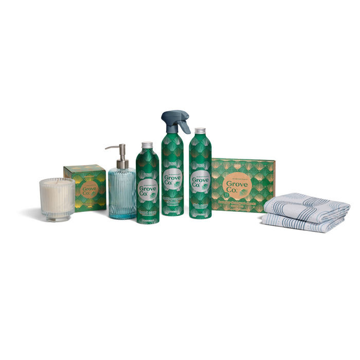 The Grove Co. Home Staples Set - Winter Collection features three bottles, a spray nozzle, a soap dispenser, a candle, two boxes, and two folded towels, all attractively arranged against a white background.