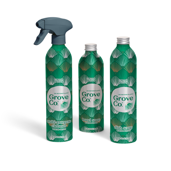 Three green metal bottles with white and teal leaf patterns labeled Grove Co. Hearth & Home Essentials - Winter Collection: a multi-purpose cleaner (spray nozzle), hand soap, and dish soap.