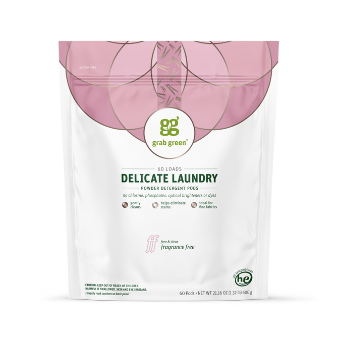 A white and pink bag of grab green Delicate Laundry Detergent Pods, fragrance free, for 60 loads. Eco-friendly packaging notes gentle cleaning, odor removal, stain-fighting power, HE compatibility, and no chlorine or dyes.
