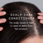 Close-up of a person parting dark hair to show their scalp, with text: Good Juju Body & Home Scalp Care Conditioner Bar—perfect for relieving dandruff and detoxing hair from product buildup with a natural formula.