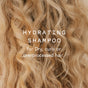 Close-up of wavy, blonde hair with overlay text: Good Juju Body & Home Hydrating Shampoo Bar. Ideal for dry, curly, or overprocessed hair—this bar controls frizz and nourishes locks effectively.