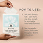 A hand holds a Good Juju Body & Home Laundry Detergent Sheet above its box, with nearby instructions demonstrating how to tear and add the eco-friendly strip to your washing machine for an easy, effective clean.