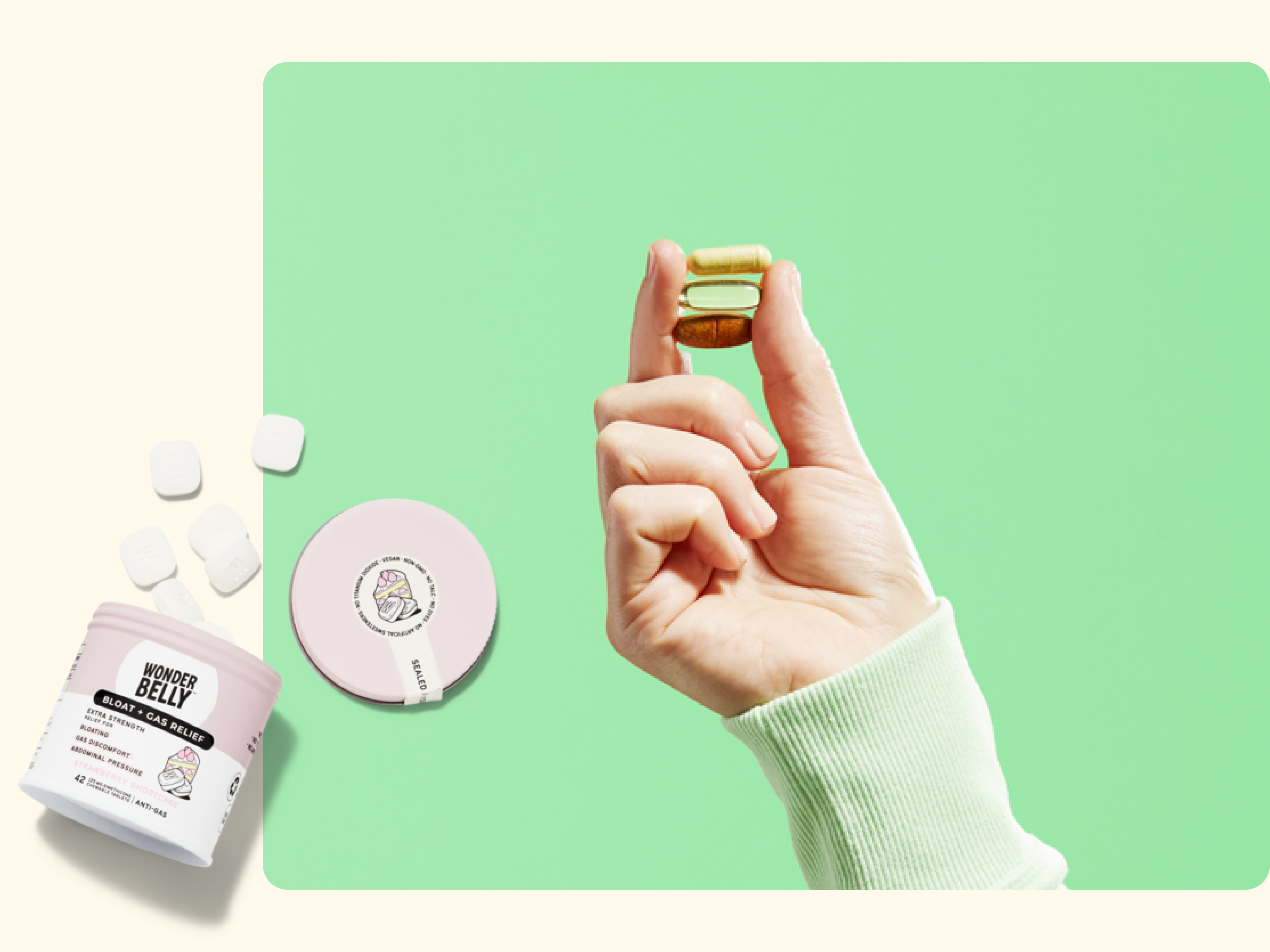 A hand in a light green sleeve holds two stacked green and beige chewable tablets. Nearby are an open container labeled Goodbye Belly with chews and a round compact, all on a light green background.
