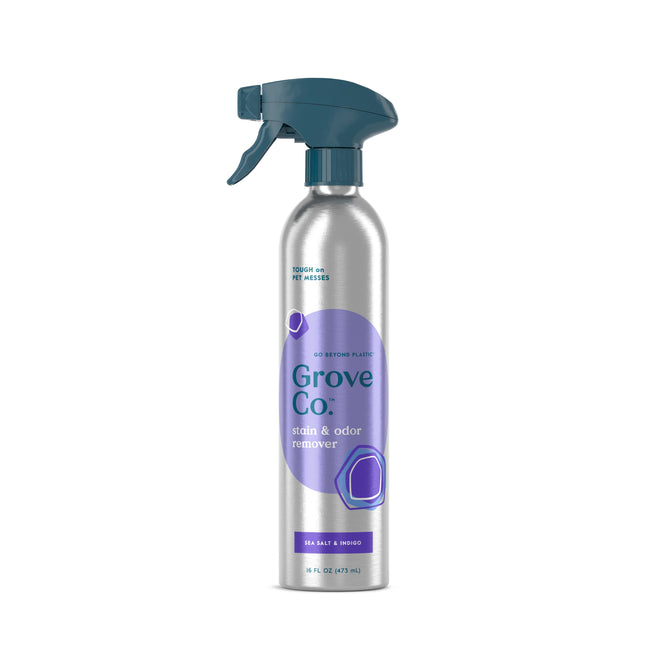 A silver Grove Co. Carpet & Upholstery Stain Remover spray bottle with a dark teal trigger and purple label, highlighting its ability to eliminate pet messes, in a refreshing sea salt & mango scent.