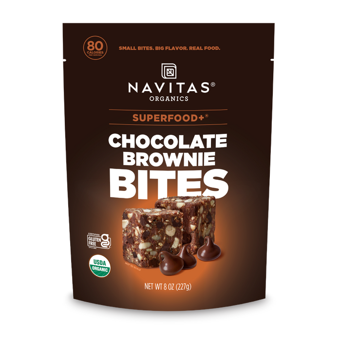 A brown resealable pouch of Navitas Organics Superfood + Chocolate Brownie BITES, with images of brownie bites and dark chocolate chips. The organic, gluten-free packaging notes 80 calories per serving and features organic cacao.
