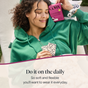 A smiling woman in a green hoodie relaxes on a chair, holding Cora Invisi-feel Daily Liner, Micro Thin and wearing a scrunchie. Text reads: Do it on the daily. So soft and flexible, our hypoallergenic micro-thin liner is designed for all-day comfort—you’ll want to wear it every day.