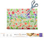 A vibrant, food-themed Beeswax Wraps for Food - Cut to Size Roll by Bee's Wrap is shown being trimmed with scissors, with the packaging displayed below. The label emphasizes its main features: no plastic, reusable, and compostable—making it an eco-friendly and customizable alternative to traditional plastic wrap in the kitchen.