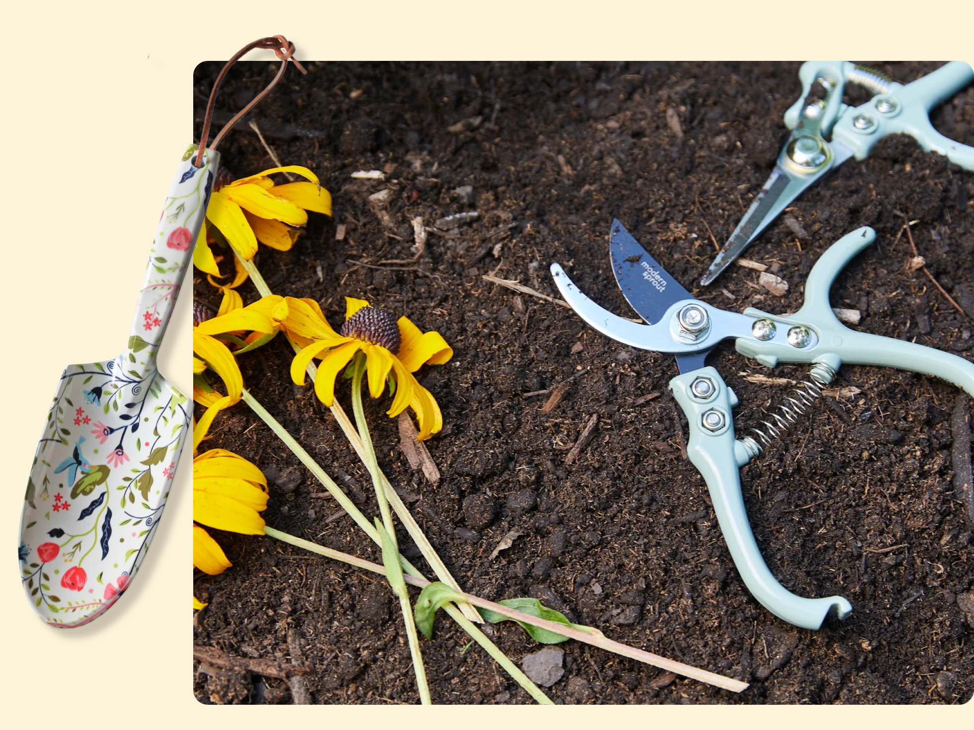 A floral-handled garden trowel, yellow flowers, and two pruning shears are arranged on dark soil, suggesting gardening activity.
