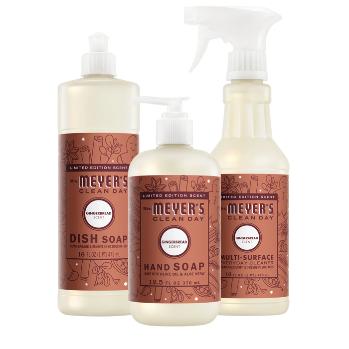 A dish soap bottle, a pump bottle of hand soap, and a spray bottle of multi-surface cleaner, all featuring gingerbread-scented labels as part of this Mrs. Meyer’s Holiday Cleaning Set – Home Essentials.