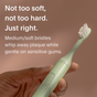 A hand holds a light green SURI electric toothbrush with white bristles. Text: Not too soft, not too hard. 3x SURI Brush Replacement Heads feature medium/soft bristles that remove plaque gently for sensitive teeth and gums.