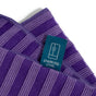 A close-up of a purple striped microfiber cloth from Grove Co. Assorted Cleaning Cloths, 4 pk, featuring a blue label with a refrigerator icon and the words “Stainless Steel.” Machine washable.