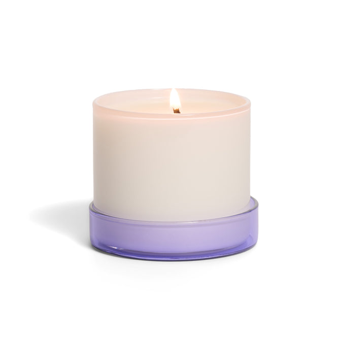 The Grove Co. Candle - 7oz features a lit white candle in a round container with a translucent purple base, displayed against a plain white background.