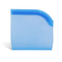 The Grove Co. Reusable Silicone Bag, in translucent blue with a rounded top corner, stands upright on a white surface—providing a sustainable food storage solution.