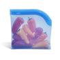Grove Co. Reusable Silicone Bag, shown in blue and leak-proof, is filled with small red and orange bell peppers for sustainable storage against a white background.