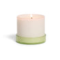 The Grove Co. Candle - 7oz is a lit white candle in a simple opaque container with a light green glass base, displayed against a white background.