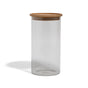 The Grove Co. Glass + Bamboo Storage Jar is a clear cylindrical container with a round, flat bamboo lid, pictured against a white background.