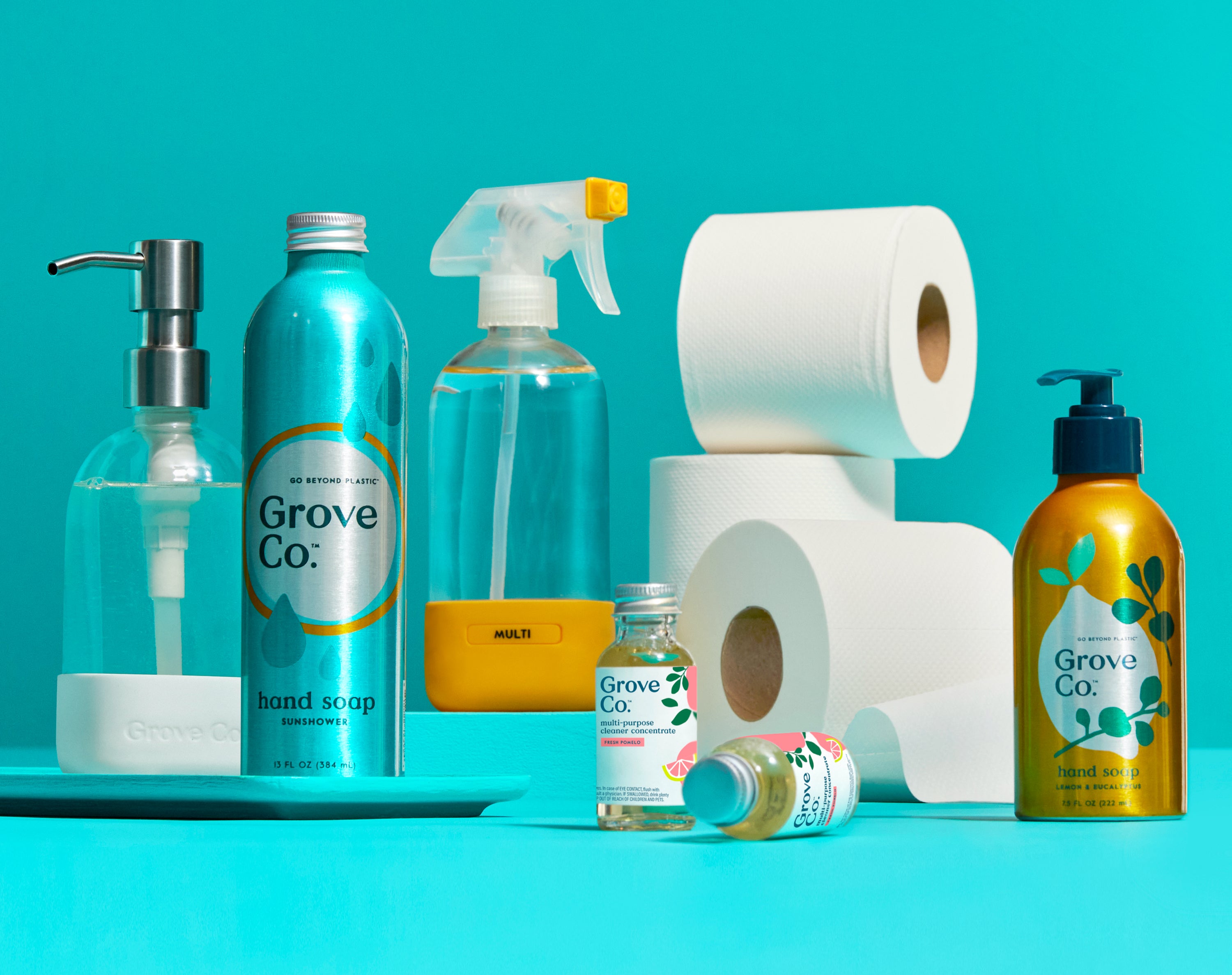 Image of a collection of products from Grove Co. Including a hand soap dispenser, hand soap refill, glass spray bottle, cleaner concentrates, and tree-free toilet paper