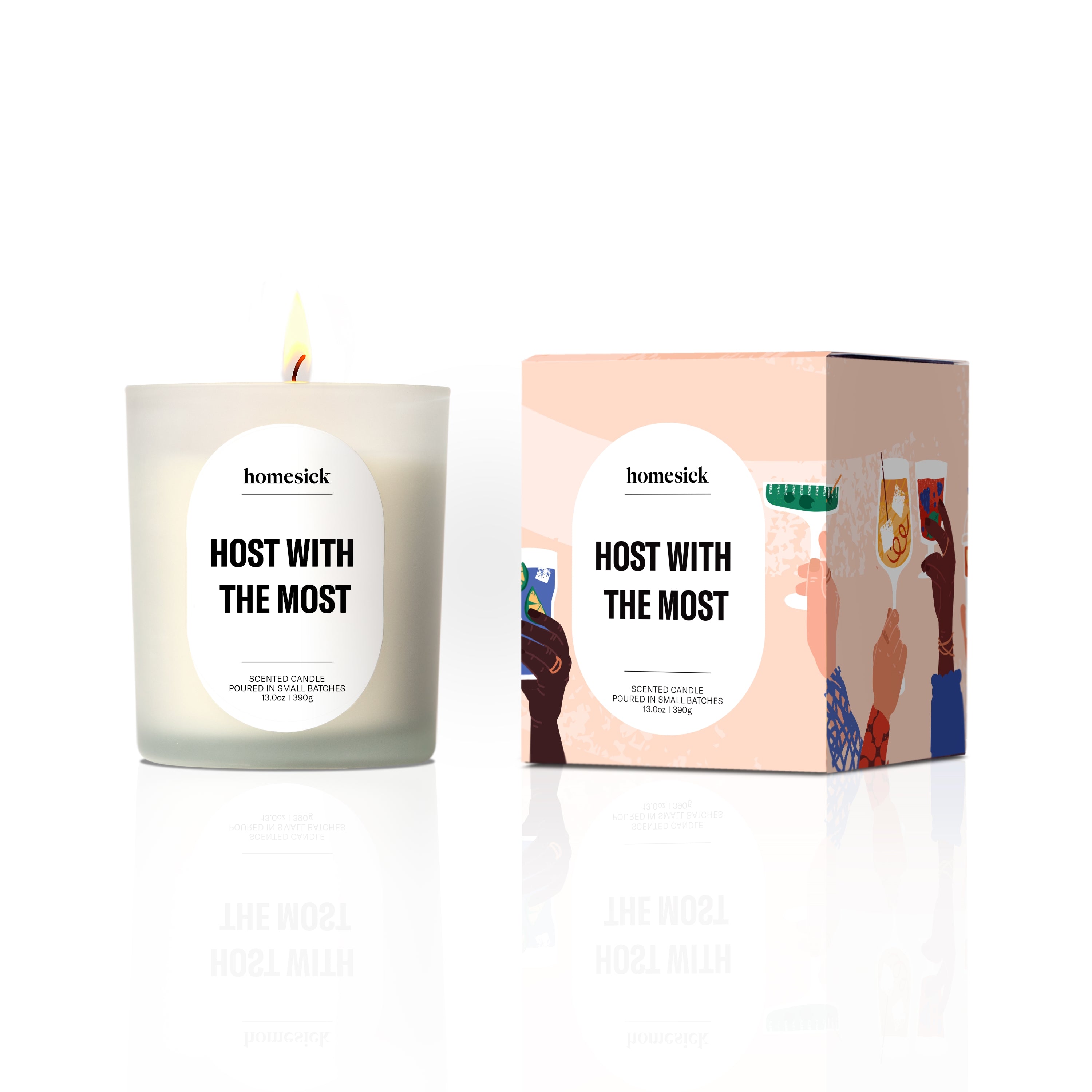 A white Hot Cider Candle by Homesick, made with natural soy wax, sits beside its box decorated with illustrations of raised hands holding drinks in a celebratory toast.