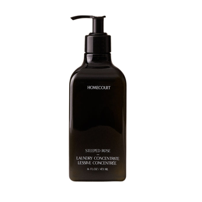 A black pump bottle of Homecourt Laundry Concentrate, 16 fl oz/473 ml, with plant-based, eco-friendly cleaning agents is shown against a white background.