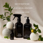 Three black bottles of Homecourt Linen Spray are displayed with green leaves, small lemons, and wool dryer balls. Text above reads: Safe for sensitive skin, made with eco-friendly ingredients and signature fragrance.