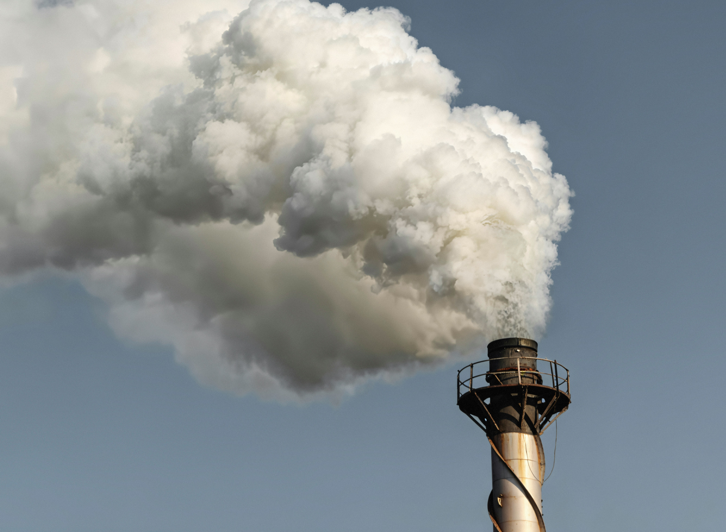Chimney emitting a large plume of smoke against a clear sky