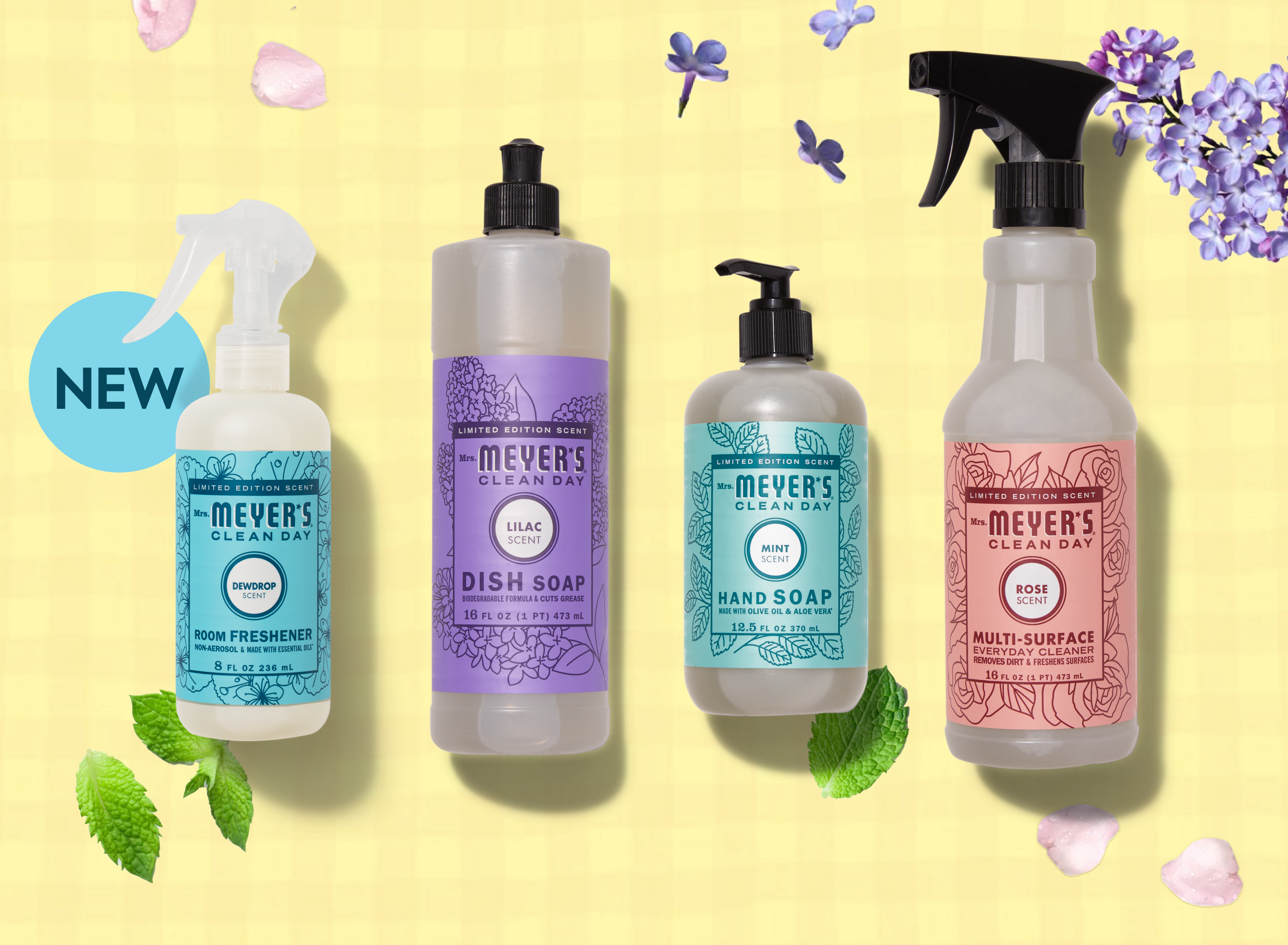 Four Mrs. Meyers Clean Day limited edition products on a yellow background: Dewdrop Room Freshener, Lilac Dish Soap, Mint Hand Soap, and Rose Multi-Surface Cleaner, surrounded by flowers and mint leaves.
